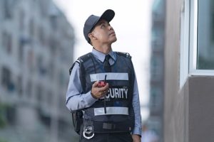 Male security guard using portable radio standing in the common building area